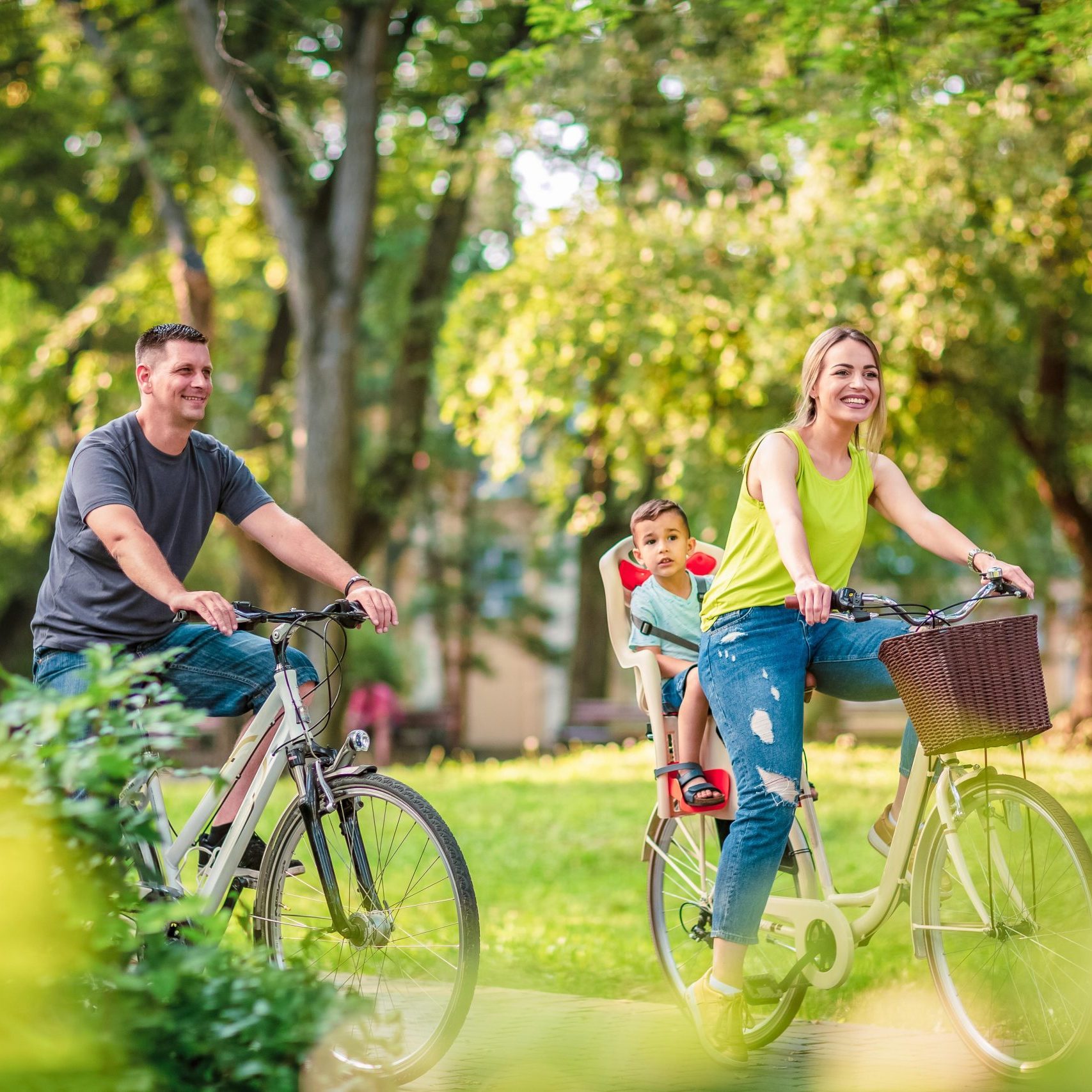 Happy family. Happy active father and mother with kid on bicycles having fun in park
